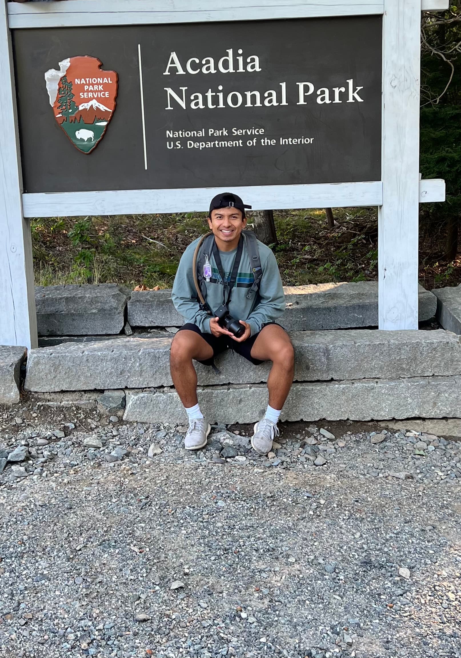 Me sitting in front of a sign for Acadia National Park